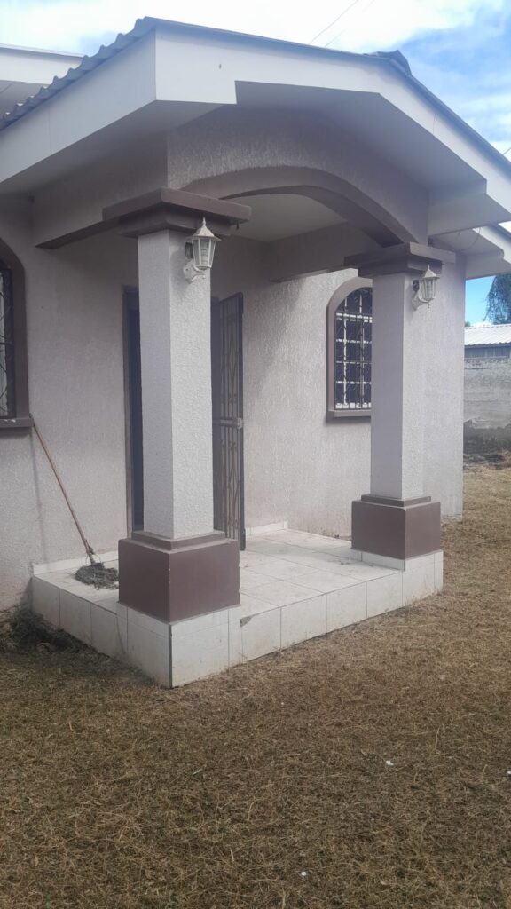 Entrada principal de casa en venta en Olanchito, con techo a dos aguas, columnas decorativas y piso cerámico.