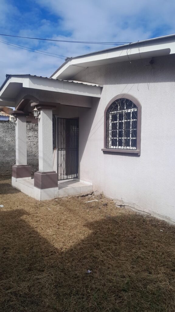 Fachada lateral de la vivienda con entrada principal y ventana enrejada