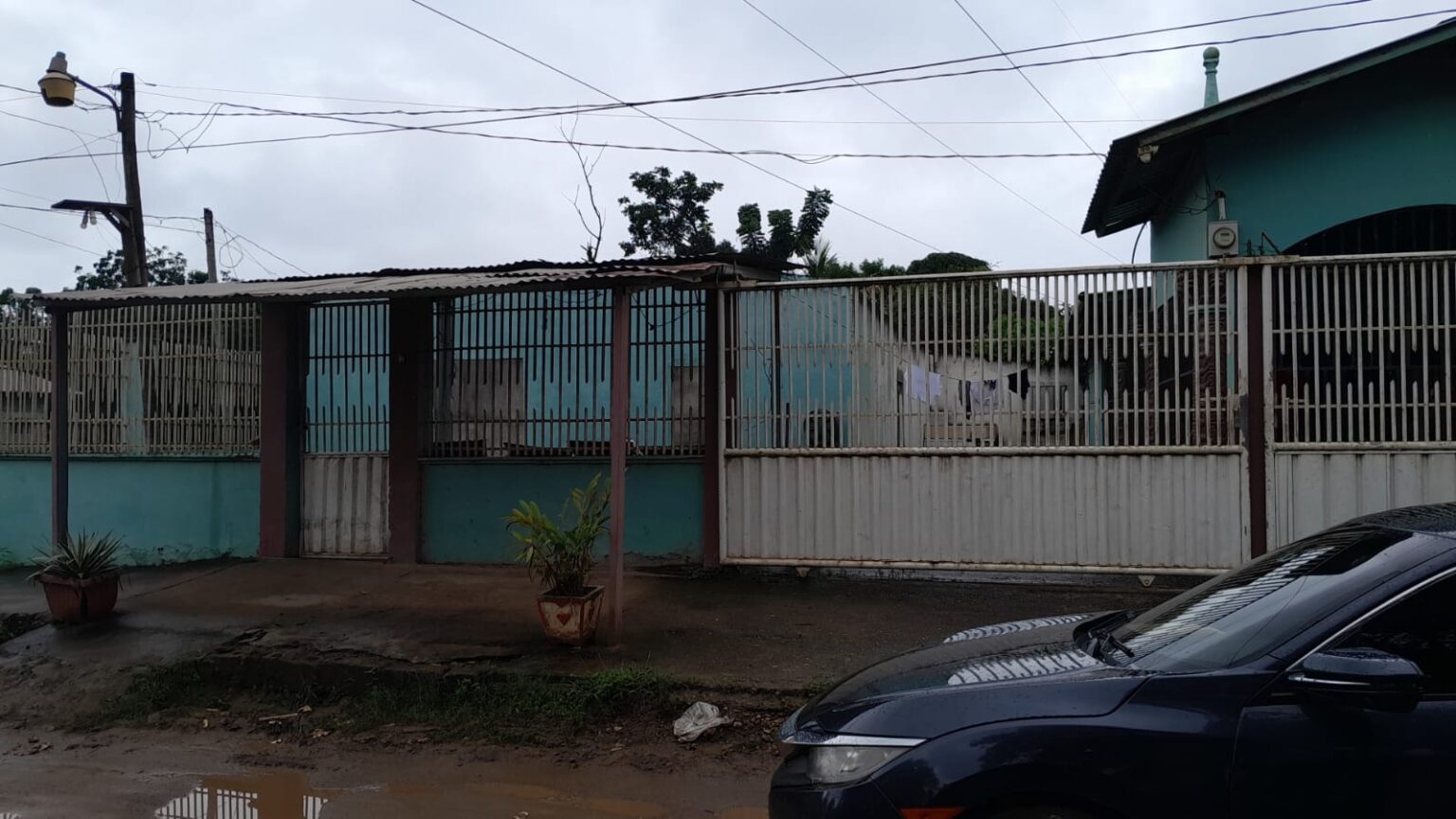 Vista exterior de vivienda con solar y estructura adicional en construcción