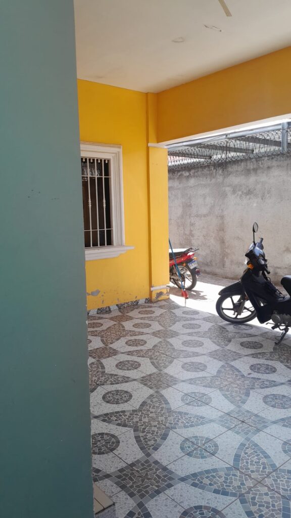 Área de estacionamiento techado con piso cerámico decorativo y muro perimetral alto