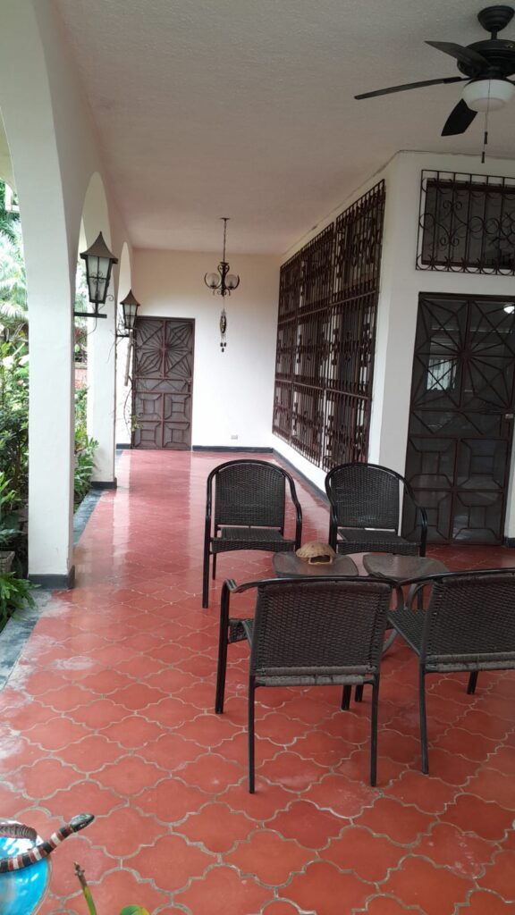 Porch amplio y elegante con ventilador de techo, sillas de mimbre y detalles coloniales en casa de dos plantas en el centro de Olanchito.