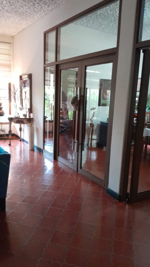 Puerta de vidrio con marcos de madera entre sala y comedor en casa de lujo en Olanchito.