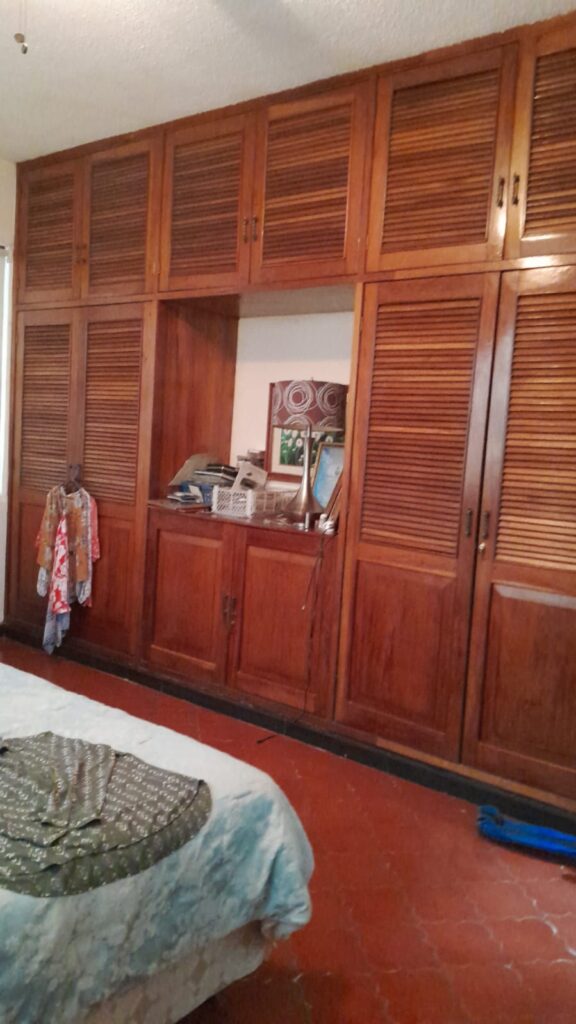 Closet empotrado de madera en dormitorio principal con múltiples compartimientos y acabados artesanales.