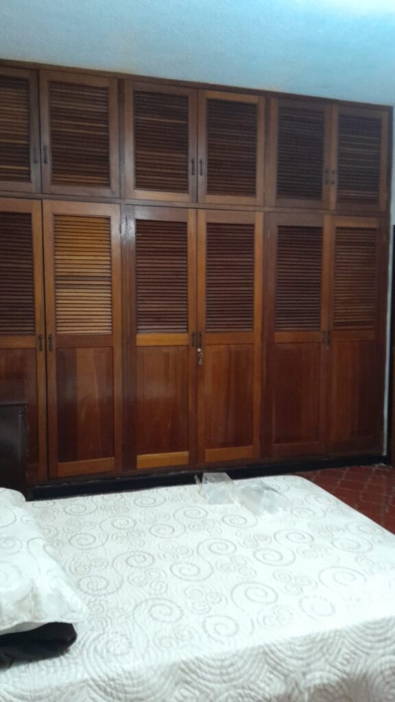 Closet empotrado de madera en dormitorio principal con múltiples compartimientos y acabados artesanales.