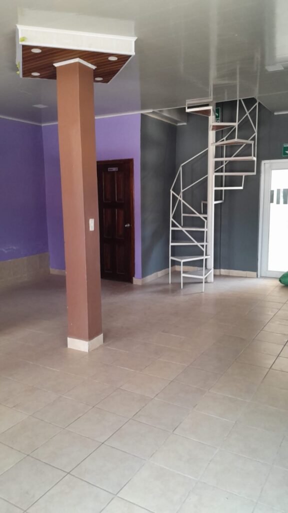 "Interior de local comercial en venta en Olanchito con escaleras de caracol hacia terraza y segundo nivel