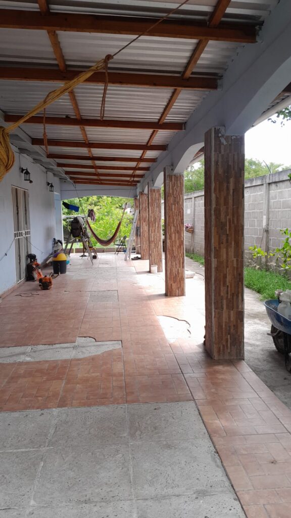 Corredor lateral con columnas decorativas y piso de cerámica en casa en venta en Medina, Olanchito