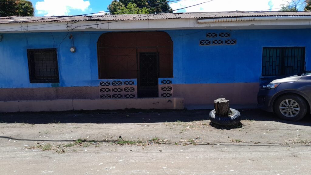 Casa en venta en Olanchito Honduras con fachada azul y acceso directo a calle pavimentada